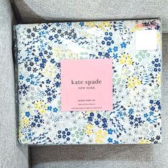 the kate spade new york notebook is sitting on top of a gray chair with a pink notepad