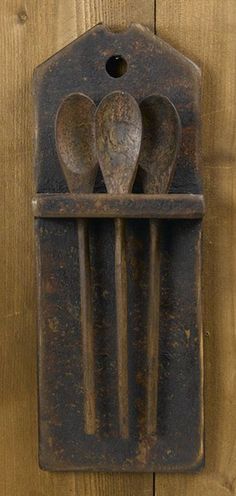 three metal spoons in a holder on a wooden wall