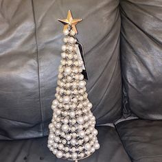 a christmas tree made out of pearls on a black leather couch with a gold star