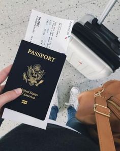 a person holding up a passport in front of a bag and luggage on the ground