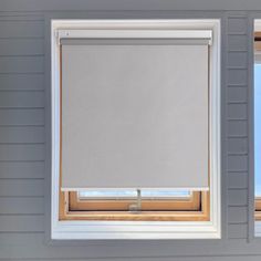 two windows with white roller shades in the same room, one is open and the other has closed