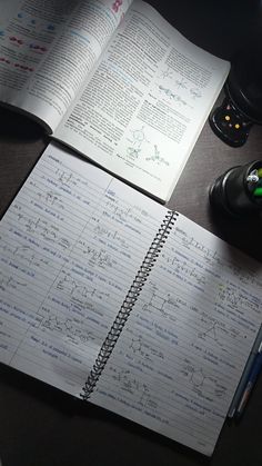 an open notebook sitting on top of a desk next to a calculator