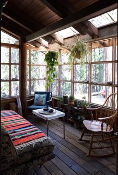 a room filled with lots of windows next to a table and chair on top of a wooden floor