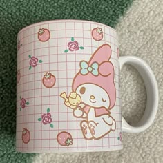 a hello kitty coffee mug sitting on top of a carpet