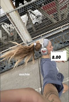 a woman with headphones on sitting next to a fence