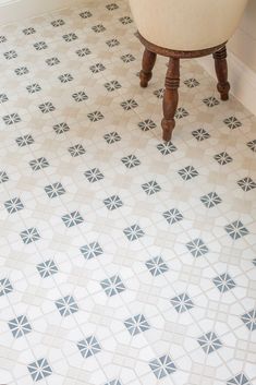 a bath tub sitting on top of a tiled floor next to a wooden stool and sink