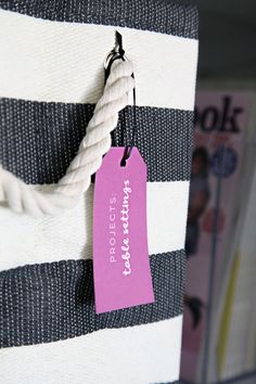 a pink tag hanging from the side of a white and black striped bag