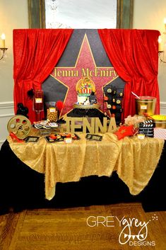 a table topped with a cake next to a red curtain and hollywood star on the wall