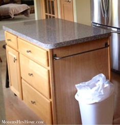 a trash can is in the middle of a kitchen island with a garbage bag on it