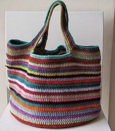 a multicolored crocheted bag sitting on top of a white shelf next to a wall