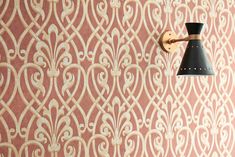 a wall mounted light on the side of a pink and gold wallpapered room