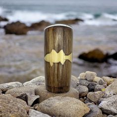 a wooden cup sitting on top of rocks near the ocean