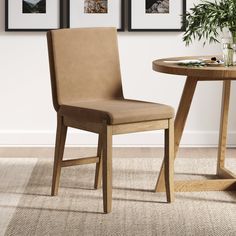 a wooden table with two pictures on the wall above it and a chair next to it