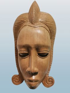 a wooden mask with an intricate design on it's face and hair in the shape of a woman's head