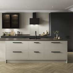 a kitchen with black and white cabinets, an island countertop and wooden flooring