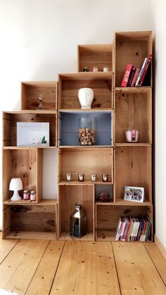 a wooden shelf filled with lots of books on top of a hard wood floor next to a white wall