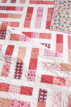 two quilts are laying on top of each other, one is red and the other is pink