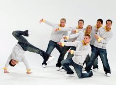 a group of men in white shirts and jeans posing for a photo with their arms spread out