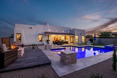 a house with a pool in the middle of it at night, and an outdoor fire pit