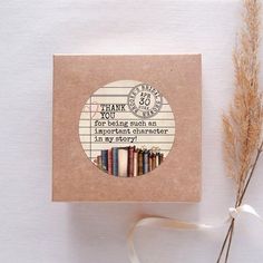 a thank you card with some books on it next to a dried plant and ribbon