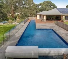 an empty swimming pool in front of a house with a solar panel on the roof