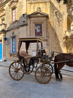 a horse drawn carriage parked in front of an old building with a painting on the wall