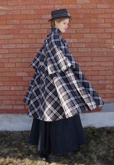 Double tiered plaid cape is lined and has a high collar with a 2-button covered button closure. In cotton plaid. Lined in satin. By Recollections and made in the USA. Cora is shown wearing a blouse, skirt, hat, tie, gloves and boots and they are priced separately. Vintage Cape Outfit, 1870s Dress, Edwardian Hat, Cape Outfit, Victorian Dresses, Plaid Capes, Clothing Reference, Regency Dress, Vintage Cape