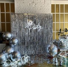 silver balls and streamers are on display in front of a wall with the word happy