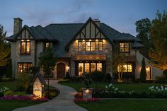 a large house lit up at night with lights on the windows and landscaping around it