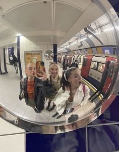 two women taking a selfie in a mirror at a subway station with their cell phone