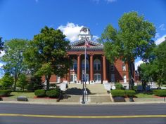 an old courthouse building on the corner of a street with trees and bushes around it