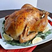 a roasted turkey on a platter with lemons and herbs