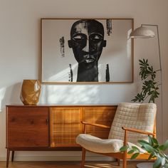 a chair sitting in front of a painting on the wall next to a wooden cabinet