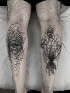 two men's legs with black and white tattoos on them, one has an eye in the middle