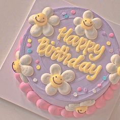 a birthday cake decorated with flowers and smiley faces