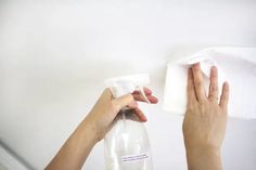 a person wiping down a bottle with a cloth on the wall next to her hand