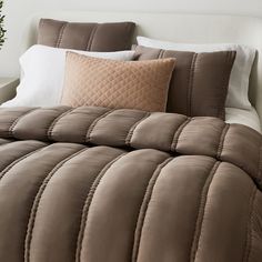 a bed with brown and white comforters on it's side in a bedroom