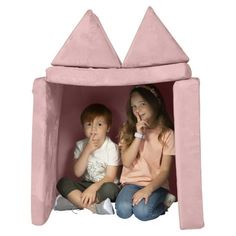 two children are sitting in a pink castle