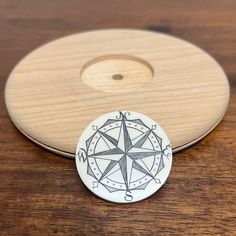 a wooden coaster with a compass design on the front and back side, sitting on a table