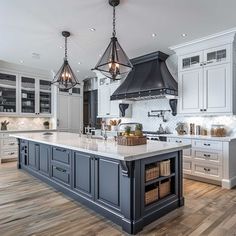 a large kitchen with an island in the middle and two pendant lights hanging from the ceiling