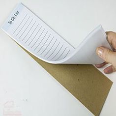 a hand holding a piece of paper on top of a brown envelope