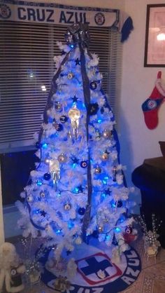 a white christmas tree with blue lights and decorations