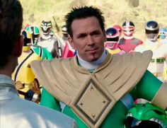 a man in a green suit standing next to a group of other men wearing costumes