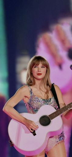 taylor swift performing on stage with her guitar