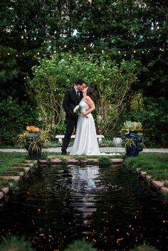 a bride and groom kissing in front of a pond