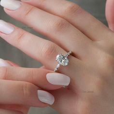 a woman's hand with white manicured nails and a diamond ring