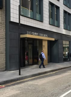 a man walking down the street in front of a building that says the capital buidix