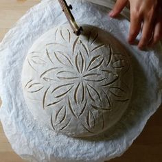 a person is carving a round object on a piece of paper