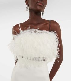 a woman in a white dress with feathers on it