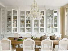 the dining room table is surrounded by white chairs and china cabinet with chandelier